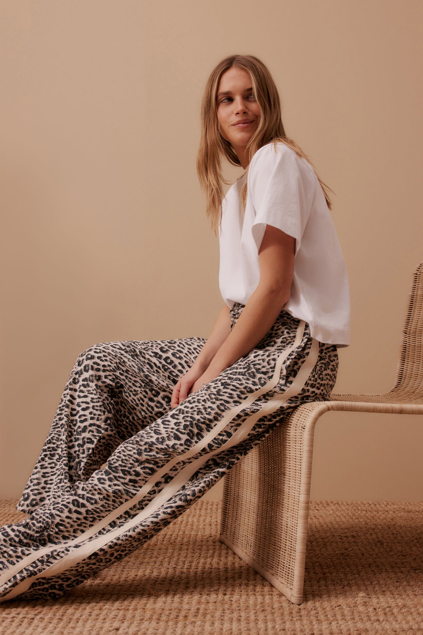Behind The Trees - Woman wearing a white blouse and leopard print pants standing against a geometric-patterned wall. - Ceres Life - Relaxed Drawstring Pant - Leopard Linen Blend