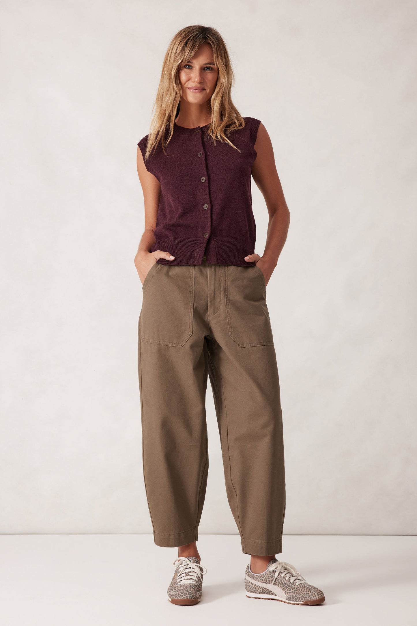 Behind The Trees - Woman wearing a sleeveless maroon top and beige pants against a white background - Ceres Life - Weekender Pant - Moss