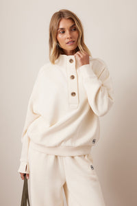 Behind The Trees - Woman wearing a cream-colored outfit with a plain background - Ceres Life - Marli Button Sweat - Marshmellow