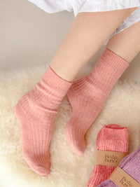 Behind The Trees - Person wearing pink socks on a fluffy white surface with 'Bee & Butter' packaging visible - Bed & Butter - The Comfiest Socks - Peach