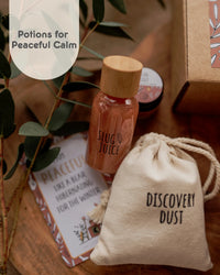 Behind The Trees - Product display with 'Slug Juice' bottle, 'Discovery Dust' bag, and decorative items on a wooden surface. - The Little Potion Co - Mini Potion Kit - Wild Adventure