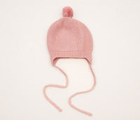 Behind The Trees - Pink knitted baby hat with a pom-pom on a light gray background - DLUX - Huggie Baby Bonnet - Garter Knit with Pompom - Pink
