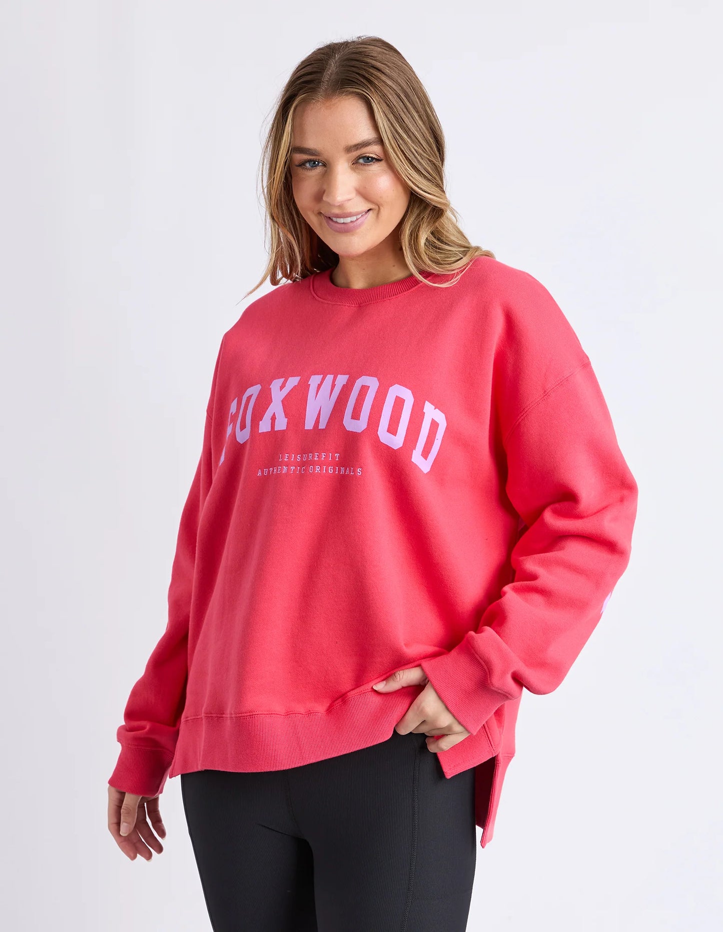 Behind The Trees - Woman wearing a red sweatshirt with 'Rockwood' text on a white background - Foxwood - Interval Crew - Raspberry & Neon Lilac