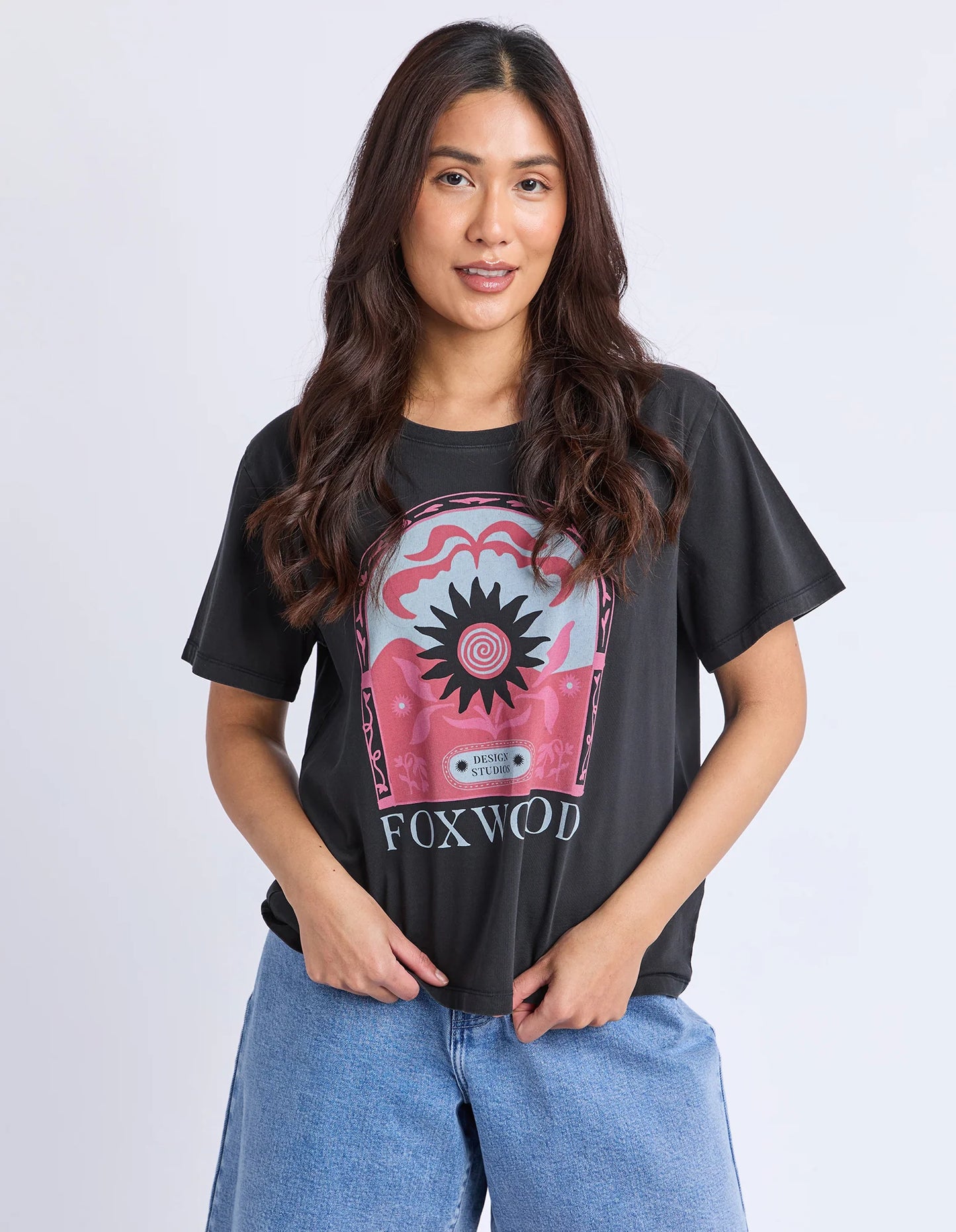 Behind The Trees - Woman wearing a black t-shirt with a graphic design and denim shorts on a white background - Foxwood - Nonchaliant Tee - Washed Black