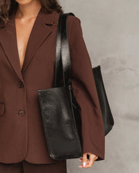 Behind The Trees- Black leather tote bag on a light gray background - Louenhide - Riley Tote Bag - Black Patent