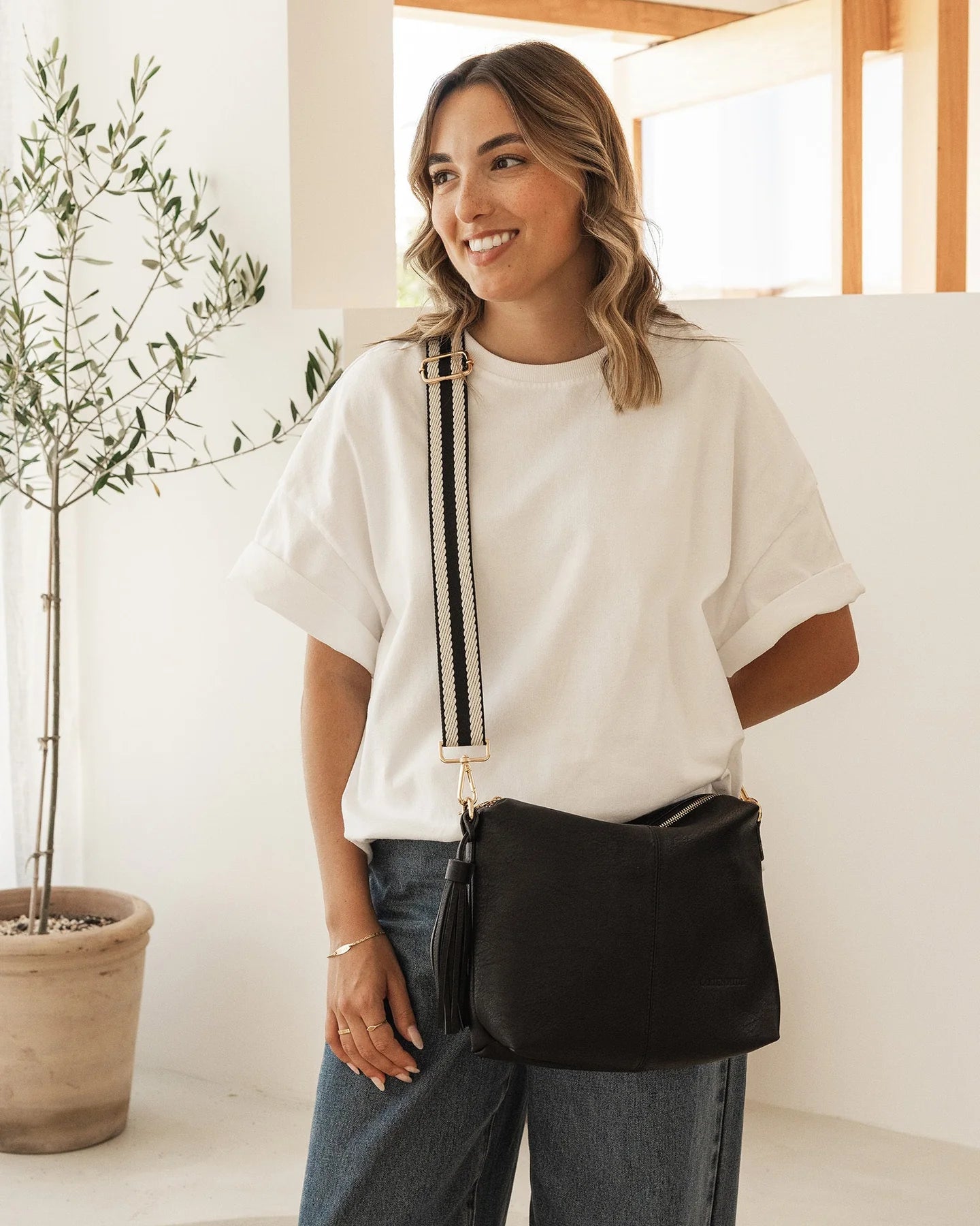 Behind The Trees - Black handbag with a strap on a light gray background - Louenhide - Daisy Stripe Crossbody Bag - Black