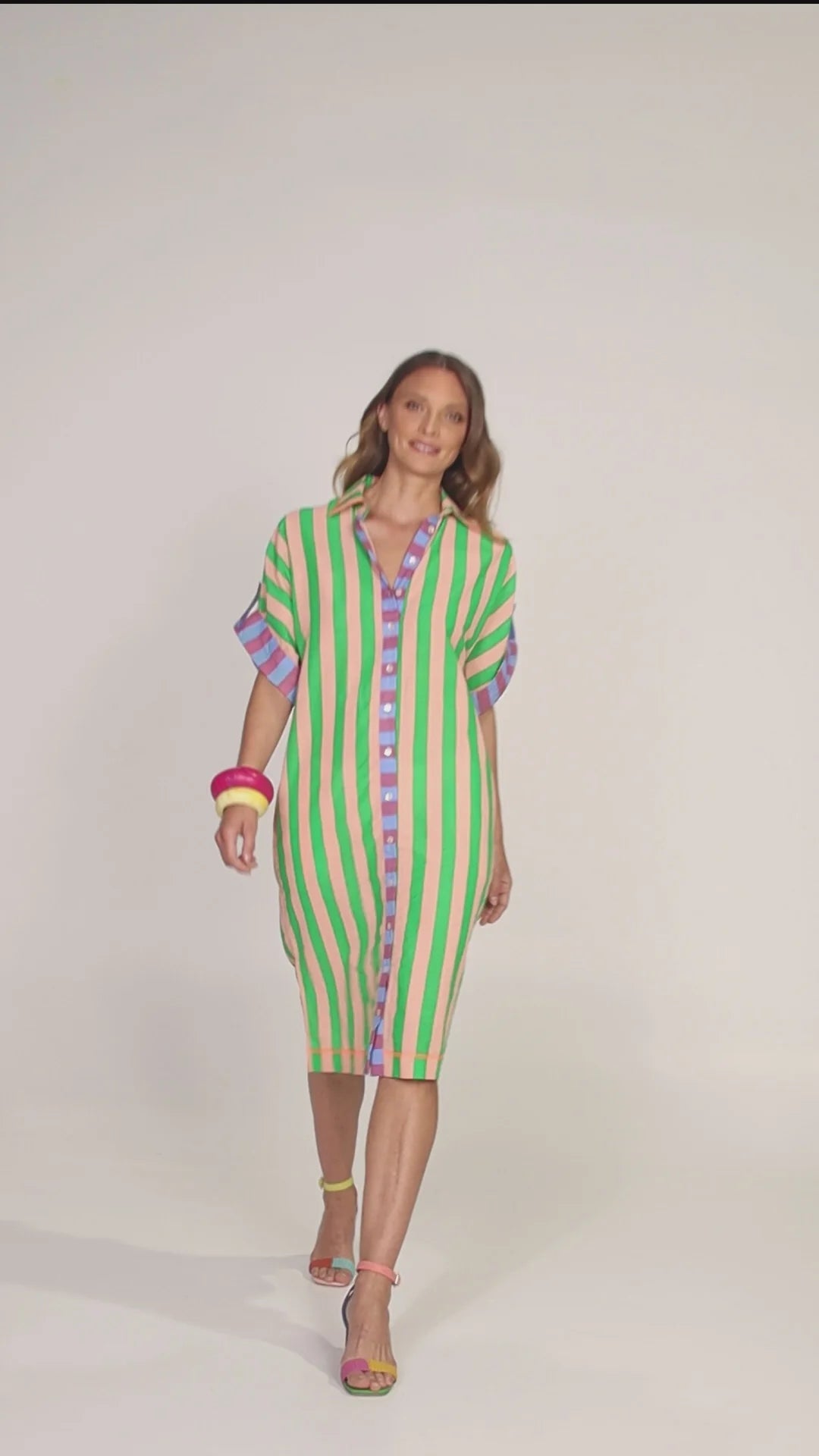 Behind The Trees - Woman wearing a green and white striped dress with colorful accents on a gray background - Boom Shankar - Maui Shirt Dress - Capri Peach