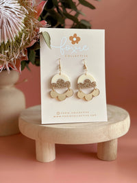 Behind The Trees - Gold earrings on a card with floral background - Foxie Collective - Foxie Earrings - Cream, Gold & Gold Glitter