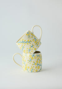 Behind The Trees - Two ceramic mugs with floral patterns stacked on a light gray background - Angus & Celeste Buttermilk Mugs - Wattle