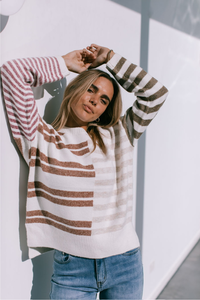 Behind The Trees - Woman wearing a striped sweater with arms raised against a light background - Miss Marlow - Abstract Stripe Knit - Chocolate/Latte