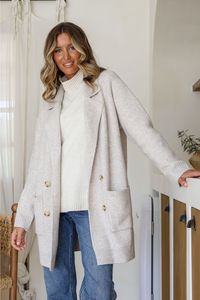 Behind The Trees - Woman wearing a long beige cardigan and blue jeans indoors. - Miss Marlow - 4 Button Pocket Coatigan - Latte