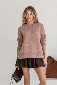 Behind The Trees - Woman wearing a brown sweater and black skirt holding a dark handbag against a neutral background - Miss Marlow - Canyon Side Split Knit - Nutmeg