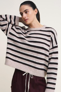 Behind The Trees - A woman wearing a cropped, long-sleeve knit sweater with horizontal black and beige stripes, paired with dark burgundy drawstring pants, against a plain light background. - Little Lies - Stripe Otto Knit - Chocoalte Stripe