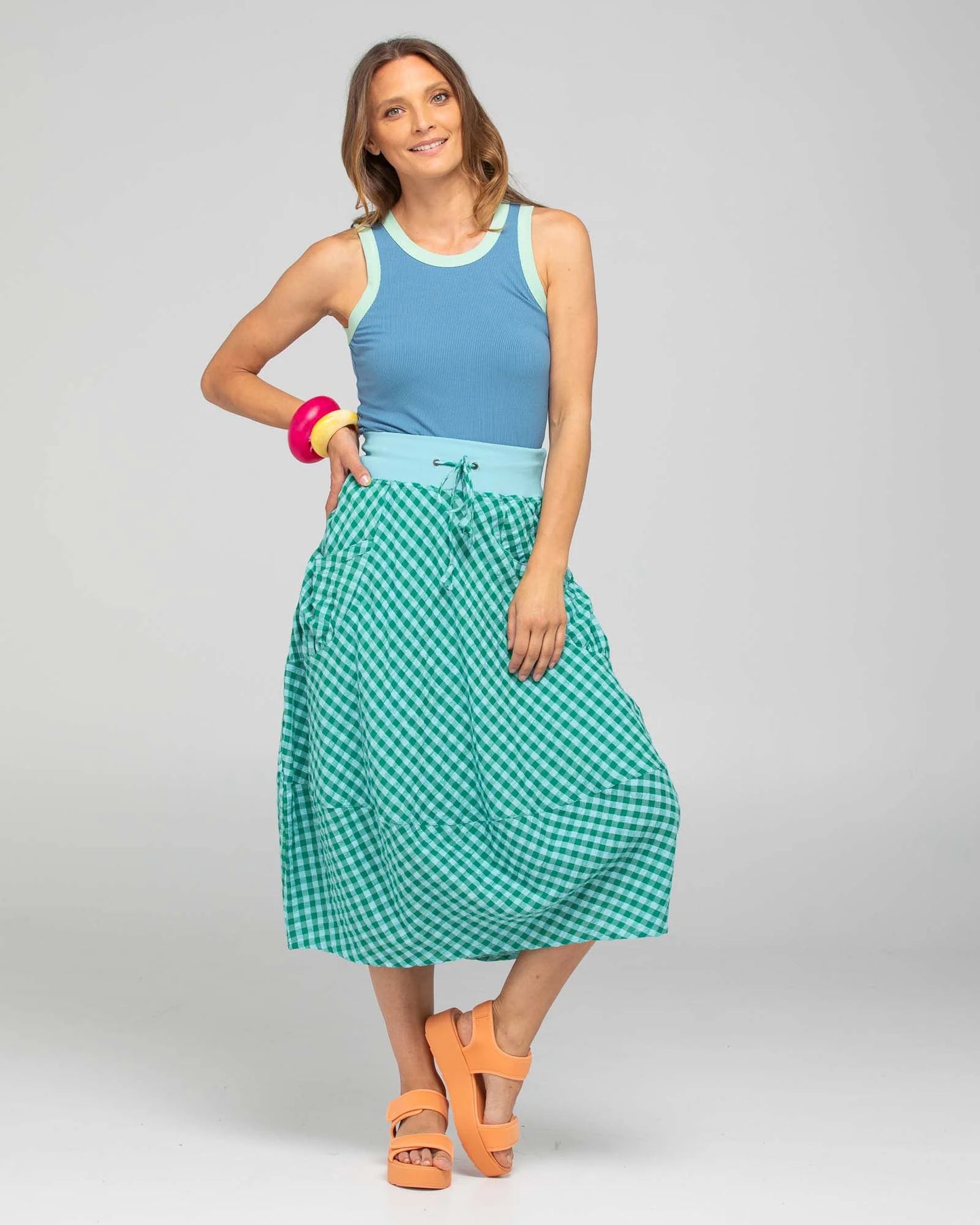 Behind The Trees - Woman wearing a blue top and green checkered skirt on a gray background - Boom Shankar - Guru Skirt - Green