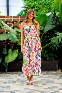 Behind The Trees - Woman in a colorful dress standing outdoors with greenery around - Boho Australia - Farfalla Strap Dress - Pink Block