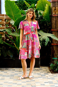 Behind The Trees - Woman wearing a colorful dress standing in front of large green leaves - Boho Australia - Perry Dress - Fushia Patch