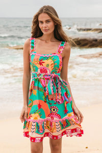 Behind The Trees - Woman wearing a colorful dress with floral patterns on a beach. - Label Of Love - Carnival Short Dress