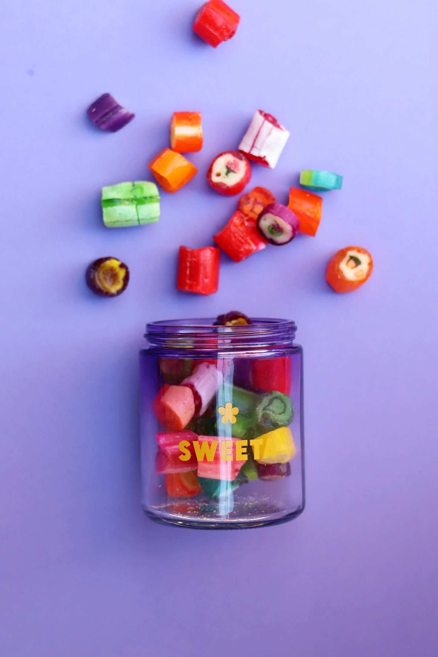 Behind The Trees - Colorful candy pieces spilling out of a glass jar labeled 'SWEET' on a purple background - Sweeta -  Fruit Salad Rock Rock 180g