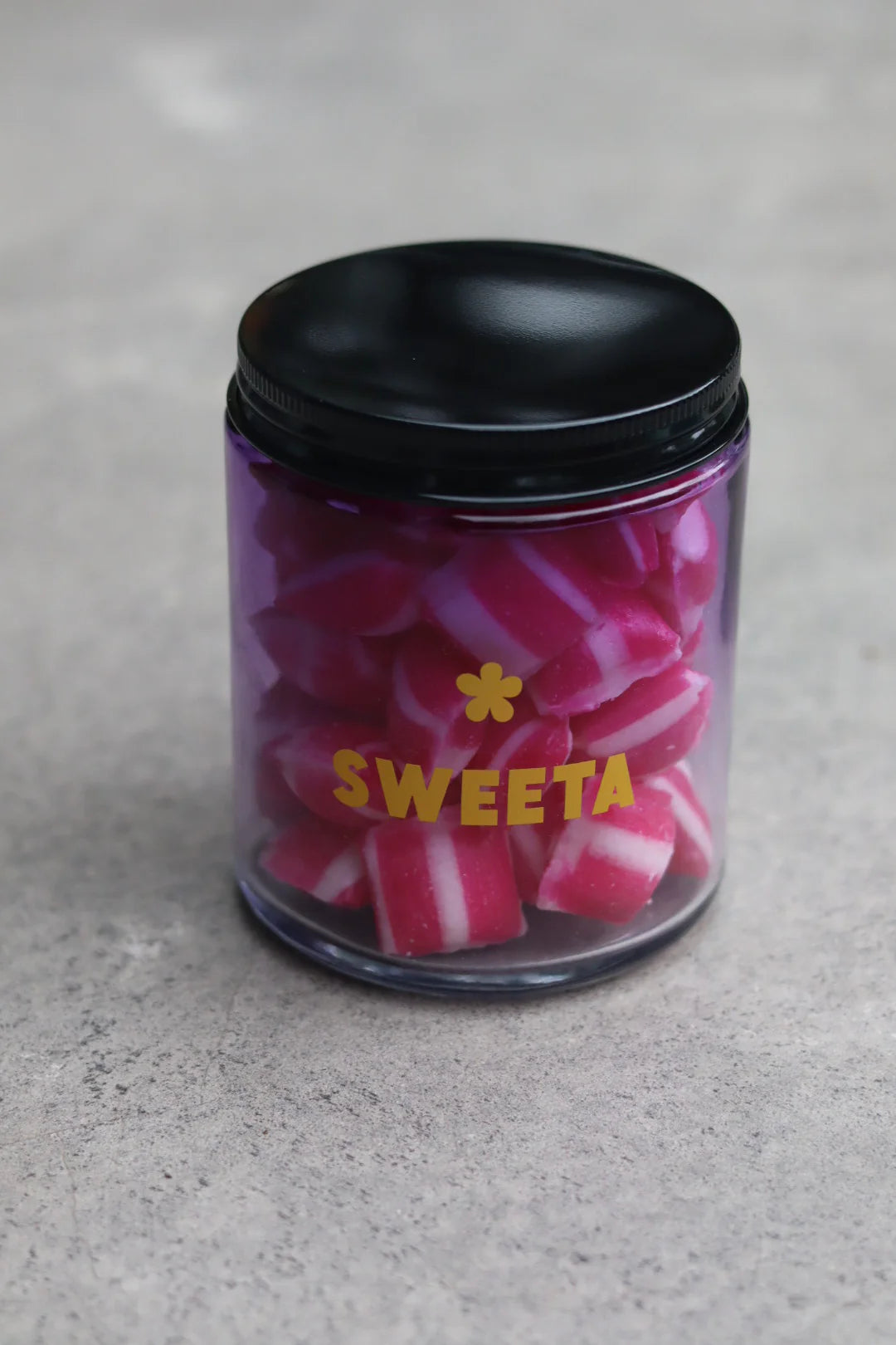 Behind The Trees - Jar of pink and white striped candies with a black lid on a gray surface - Sweeta - Raspberry Humbugs 180g