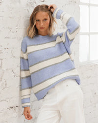 Behind The Trees - Woman wearing a blue and white striped sweater against a white brick wall. - Paper Heart - Pina Stripe Knit Jumper - Blue