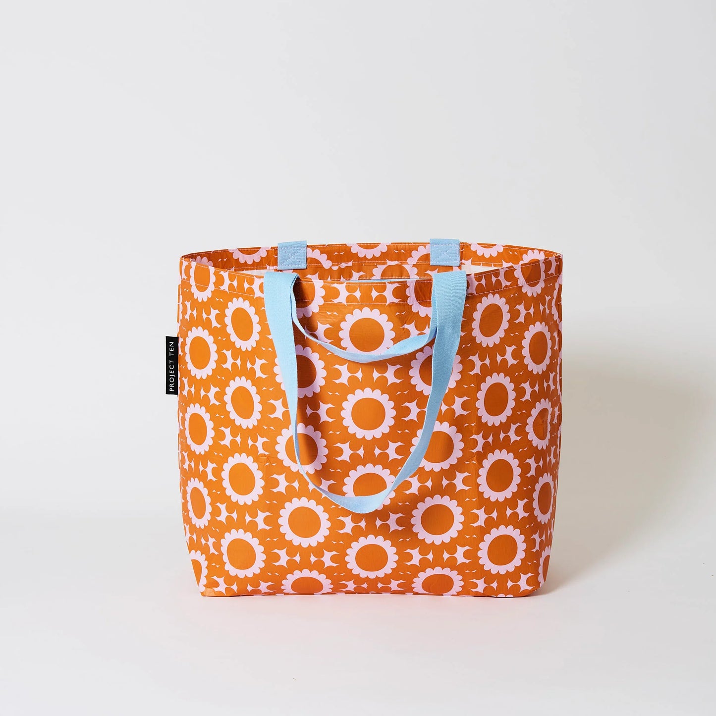 Behind The Trees - Orange tote bag with floral pattern and blue handles on a white background - Project Ten - Medium Tote - Geo Floral