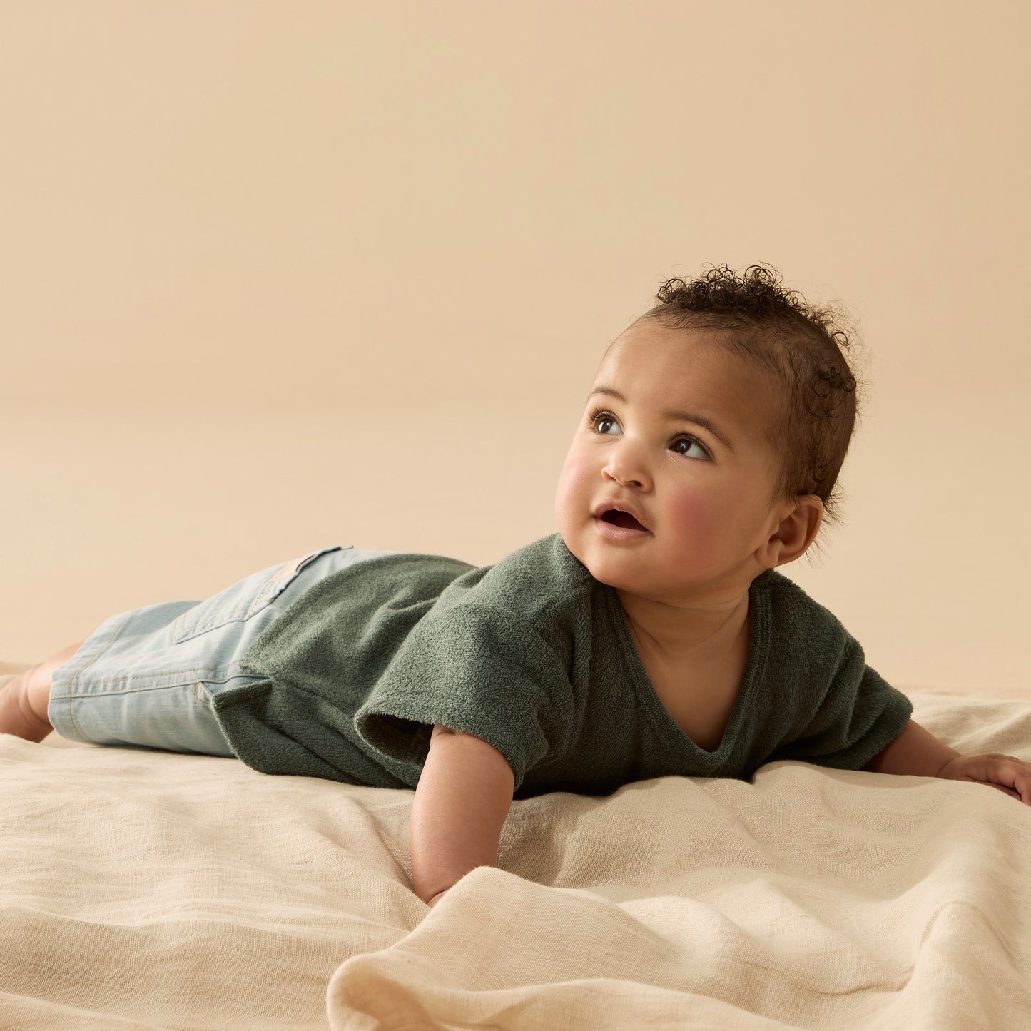 Behind The Trees - Baby lying on a beige blanket against a beige background - Wilson + Frenchy - Organic Terry Tee - Moss