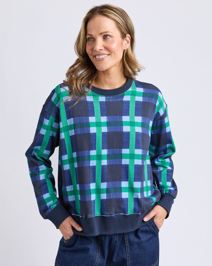 Behind The Trees- Woman wearing a blue and green plaid sweater against a white background -Elm - Bari -Blue Check-Crew
