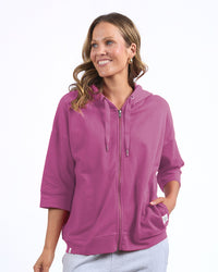 Behind The Trees - A woman wearing a magenta pink zip-up hoodie with drawstrings and a front pocket, paired with light gray sweatpants, photographed against a solid white background. - Elm - Beachy Zip Hoodie - Magenta