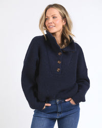 Behind The Trees - Woman wearing a navy blue sweater with a high collar on a white background - Elm - Bron Button Knit - Dark Sapphire