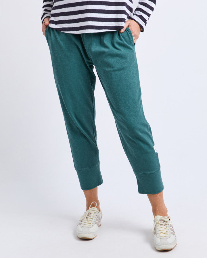 Behind The Trees- Person wearing teal jogger pants and a striped shirt on a white background- Elm brunch-pant-teal