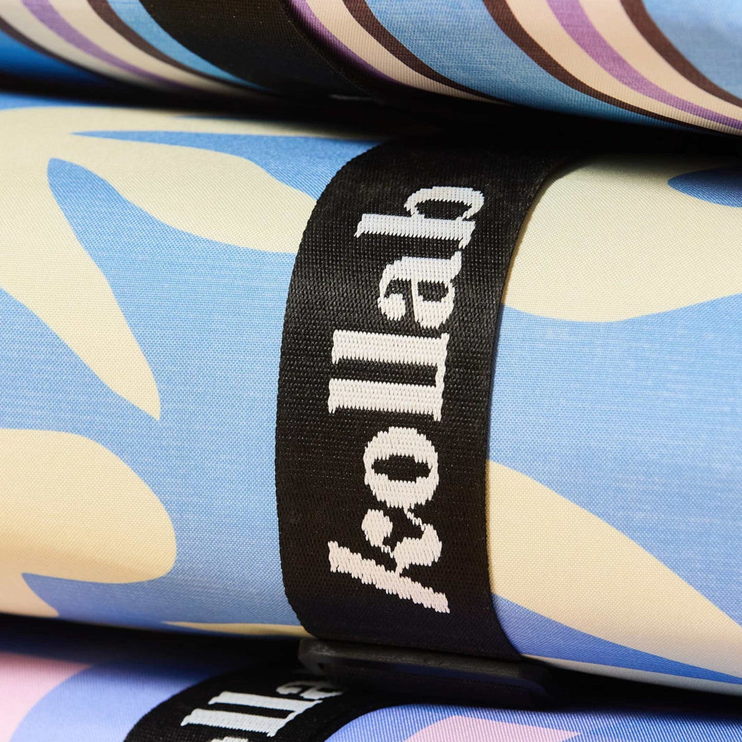 Behind The Trees - Folded towel with blue and white leaf pattern and 'kollab' branding on a black strap. - Kollab - Picnic Mat - Butter Blue