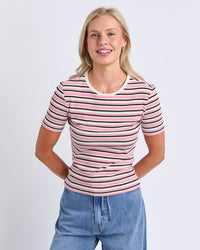 Behind The Trees - A woman wearing a short-sleeve crewneck t-shirt with horizontal pink, black, and white stripes, paired with blue jeans, against a light gray studio background. - Chocberry Tee - Choc & Pink Stripe