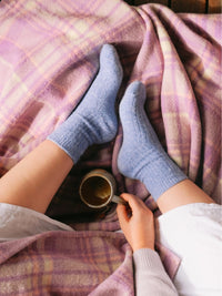 Behind The Trees - Person wearing blue socks and holding a mug on a plaid blanket - Bed & Butter - The Comfiest Socks - Lavender
