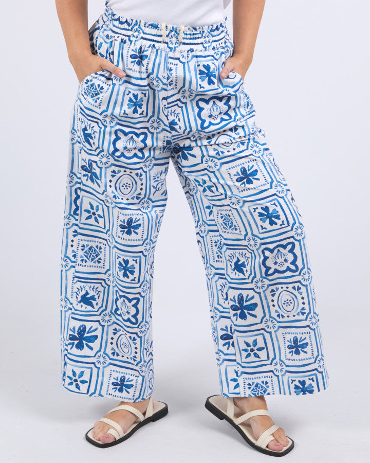 Behind The Trees - Blue and white patterned pants worn by a person on a white background - Elm - Dolce Tile Pant - Ocean Tile Pant