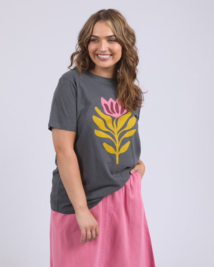 Behind The Trees - Woman wearing a gray t-shirt with a pink and yellow floral design on a plain background - Elm - Fiore Tee - Charcoal
