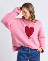 Behind The Trees- Woman wearing a pink sweater with a red heart design on a light gray background - Elm - Intersia-Heart-Knit