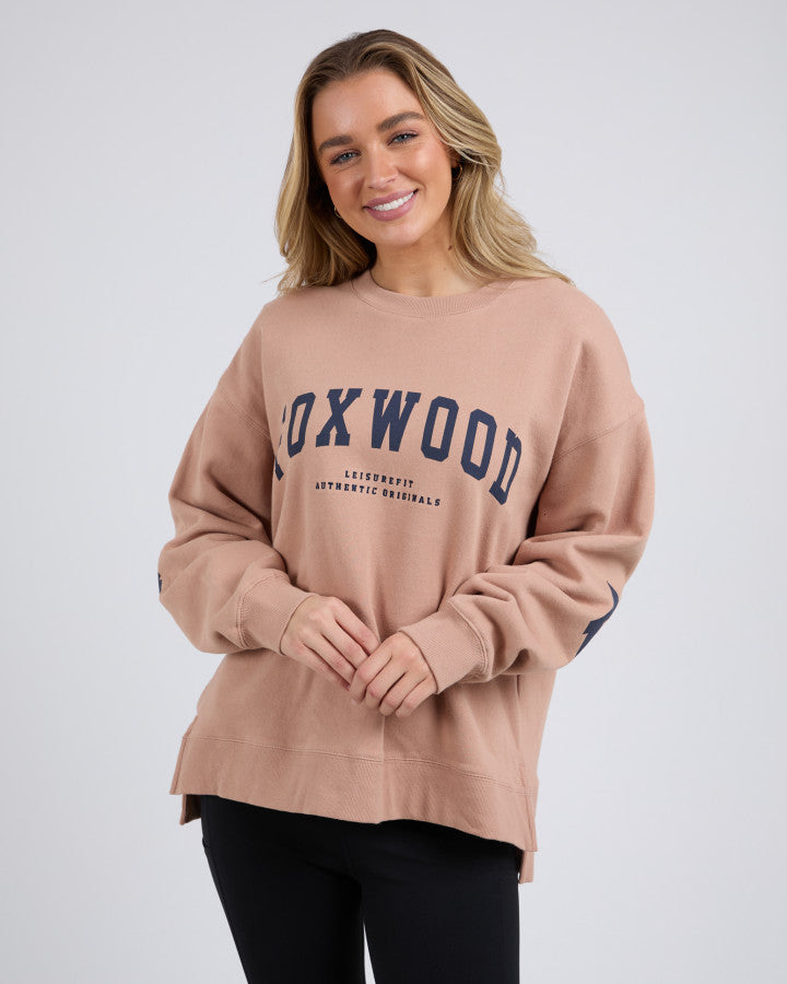 Behind The Trees - Woman wearing a beige sweatshirt with 'Foxwood' text on a plain background - Foxwood - Interval Crew - Tan