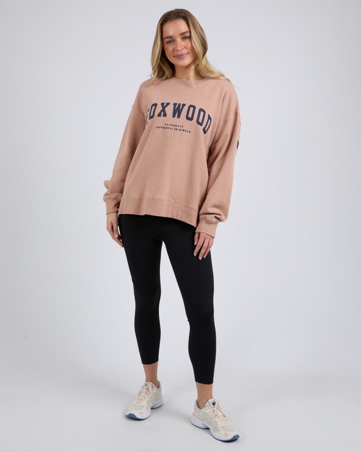 Behind The Trees - Woman wearing a beige sweatshirt with 'Foxwood' text on a plain background - Foxwood - Interval Crew - Tan