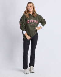 Behind The Trees - Woman wearing a green 'FOXWOOD' sweatshirt on a white background - Foxwood - Interval Hoodie - Dark Khaki With Coral 