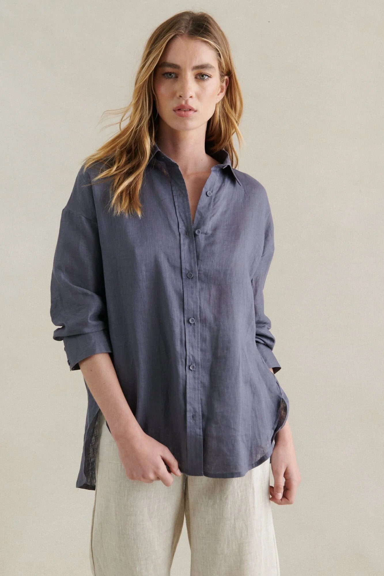 Behind The Trees - Woman wearing a blue button-up shirt and beige pants against a neutral background - Little Lies - Boyfriend Linen Shirt - Steel