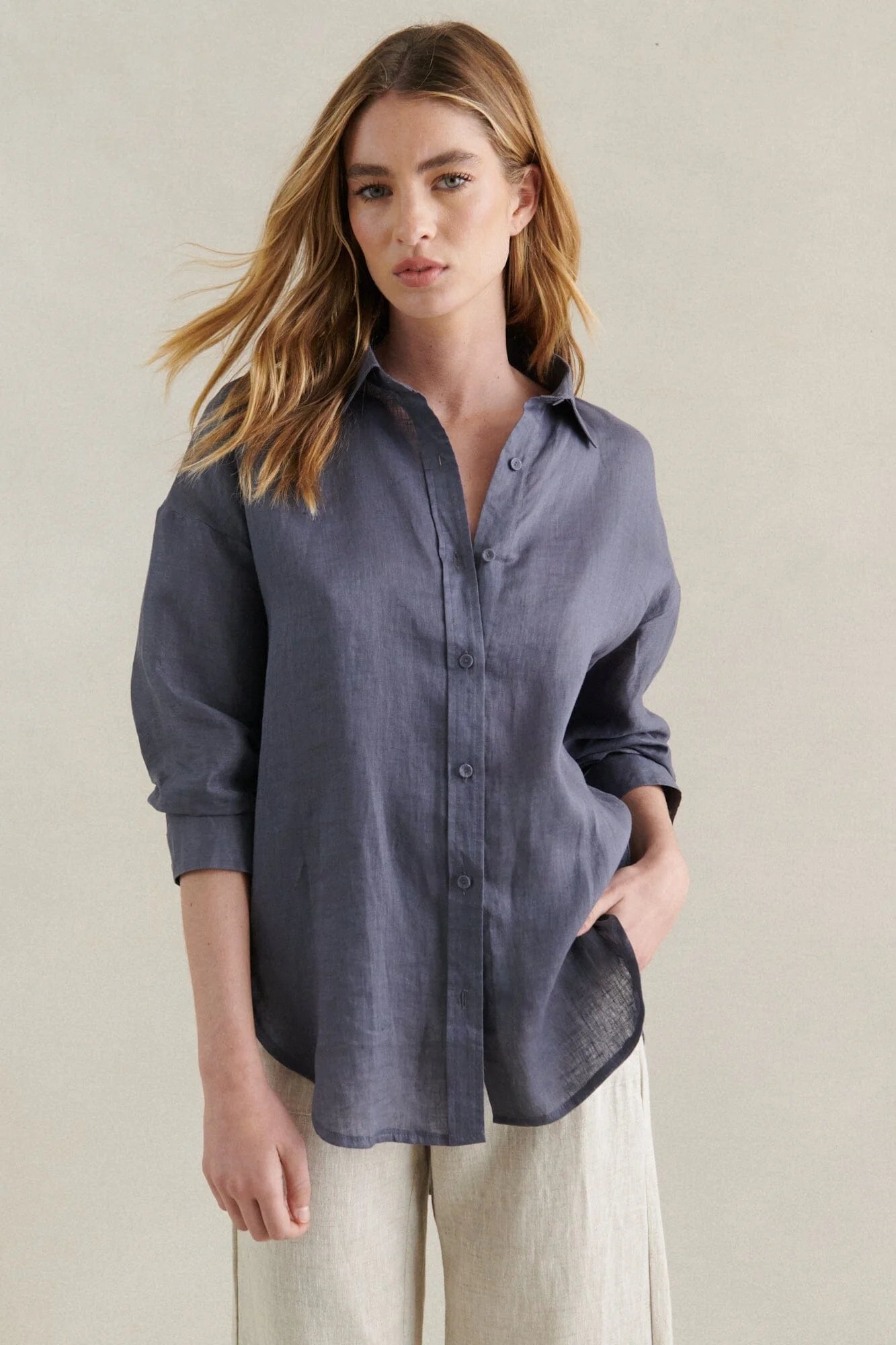 Behind The Trees - Woman wearing a blue button-up shirt and beige pants against a neutral background - Little Lies - Boyfriend Linen Shirt - Steel