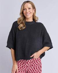 Behind The Trees - Woman wearing a black knit sweater with a plain background - Elm - Luela Short Sleeve Knit - Black