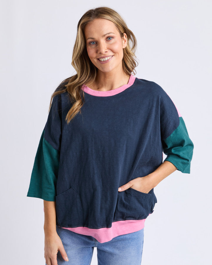 Behind The Trees- Woman wearing a navy sweater with green sleeves and pink trim on a white background-Elm - Mazie Sweat - Navy/Quartz Pink