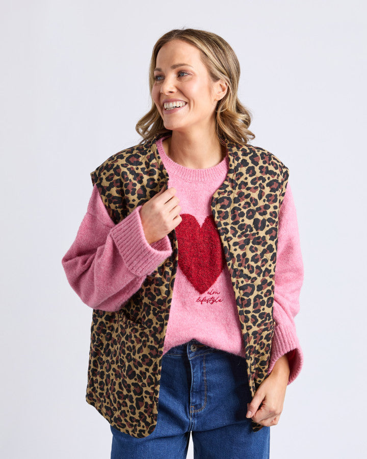 Behind The Trees - Woman wearing a leopard print vest over a pink sweater with a red heart design. - Elm - Saskia Vest - Animal Print
