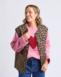 Behind The Trees - Woman wearing a leopard print vest over a pink sweater with a red heart design. - Elm - Saskia Vest - Animal Print