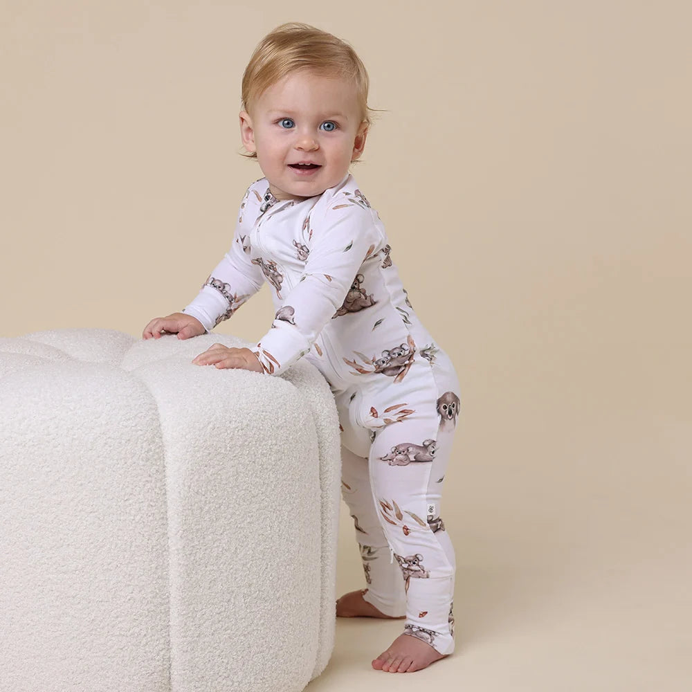 Behind The Trees - Baby wearing a white onesie with animal prints on a beige background - Snuggle Hunny - Organic Snugglesuit Convertible Romper - Koala